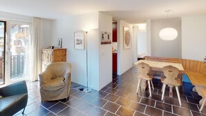 Ein Zimmer mit Esstisch, Stühlen, einer Couch und einem Schrank.