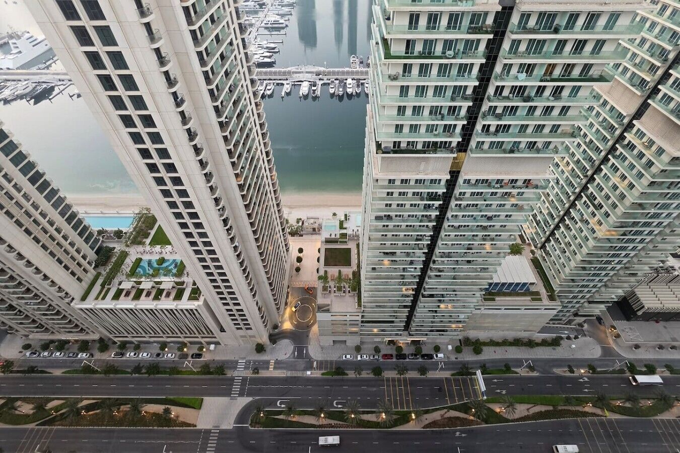 A high-rise building with a marina in the background, featuring multiple balconies and a central courtyard.