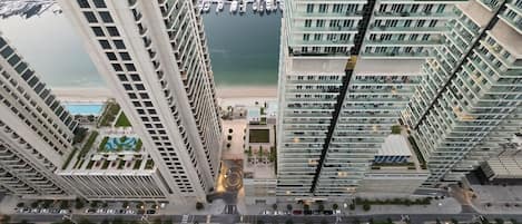 A high-rise building with a marina in the background, featuring multiple balconies and a central courtyard.