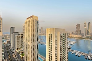 A high-rise building with a marina and boats in the background. - FIRST CLASS |1BR| Beachfront with Ain Dubai Views (Dubai Harbour)