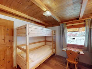 A bunk bed room with a wooden ceiling, a desk with a chair, and a window with curtains. - Apartment Stalla Bodmer by Interhome (Samedan)