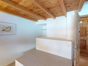 A room with a wooden ceiling, a white wall with a framed picture, and a door with a wooden frame. - Apartment Stalla Bodmer by Interhome (Samedan)