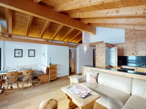 Un salón acogedor con techo de madera, un sofá, una mesa de centro y un comedor con sillas y una mesa.