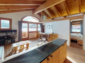 A cozy cabin interior with a dining area, a kitchen with a black countertop, and a bed. - Apartment Stalla Bodmer by Interhome (Samedan)