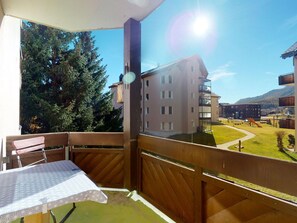 A balcony with a table and chairs, overlooking a residential area with houses and a playground. - Apartment Promulins B4 by Interhome (Samedan)