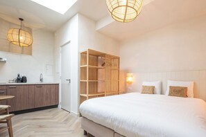 Een moderne hotelkamer met een groot bed, een houten kledingkast, een kitchenette en een dakraam.