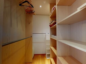 A narrow walk-in closet with wooden shelves and a metal rod. - Apartment Sur Puoz 2A by Interhome (Samedan)