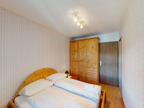 Ein Schlafzimmer mit einem hölzernen Bett, einem Kleiderschrank und einer Deckenleuchte.