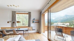 En modern inredning med ett matområde, sittplatser och ett stort fönster med utsikt över bergen.