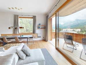 A modern interior with a dining area, seating, and a large window offering a mountain view. - Apartment Margnetta by Interhome (Maloja)