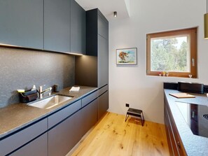 Eine moderne Küche mit dunklen Schränken, einer Holz Arbeitsplatte und einem Fenster mit Blick auf Bäume.