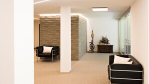 Um interior moderno com dois sofás de couro preto, um armário de madeira com um vaso e uma parede de pedra.