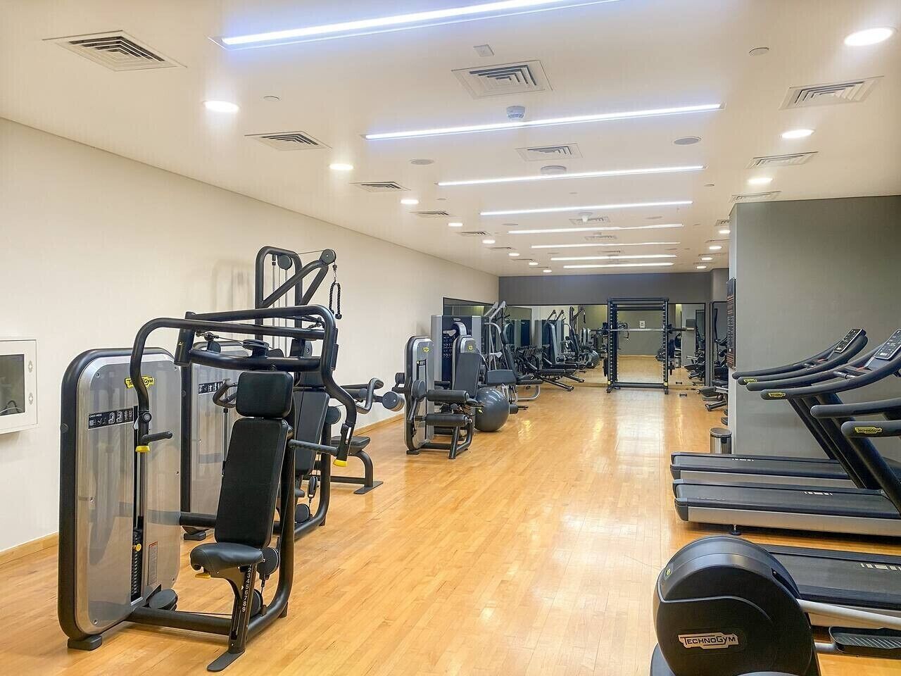 Un gimnasio con equipo de ejercicio, cintas de correr y un espejo grande.