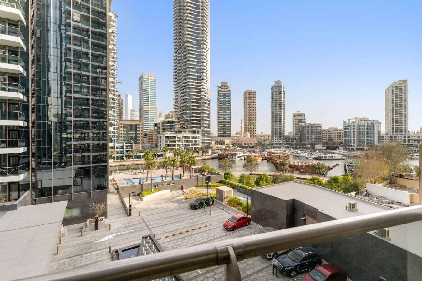 Ein Hochhaus mit modernem Design, das einen Dachbereich mit Pool und eine Marina mit Booten zeigt.