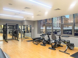 A gym with exercise equipment, large windows, and a wooden floor. - FIRST CLASS | 2BR | Sophisticated Marina Living (Marina)