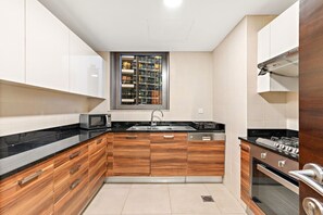 Une cuisine moderne avec des meubles en bois, un évier en acier inoxydable, un four à micro-ondes, un lave-vaisselle et une cuisinière.