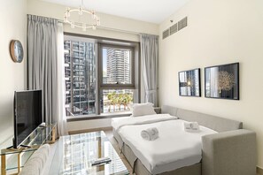 A hotel room with a bed, a sofa, a TV, and a window with a city view. - FIRST CLASS | 2BR | Sophisticated Marina Living (Marina)