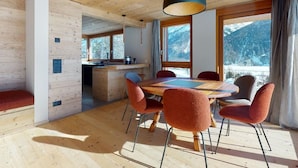 Un interior de madera con comedor, ventanas amplias y vistas a montañas.