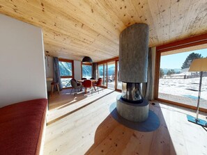 A spacious room with a wooden ceiling, large windows, a fireplace, and a view of the outdoors. - Apartment Quadrellas 3.5 by Interhome (Samedan)