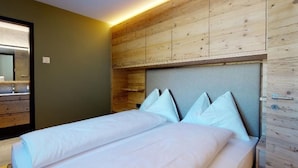 Una cama doble con ropa blanca y un cabecero frente a una pared de madera.