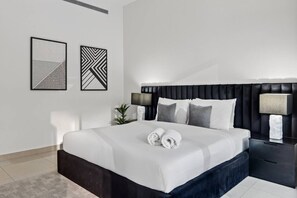 A modern hotel room with a large bed, two bedside tables, and two wall-mounted lamps. - FIRST CLASS | 2BR | Luxury Retreat | Near Downtown (Business Bay)
