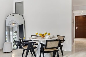 A dining area with a round table, black chairs, and a modern light fixture. - FIRST CLASS | 2BR | Luxury Retreat | Near Downtown (Business Bay)