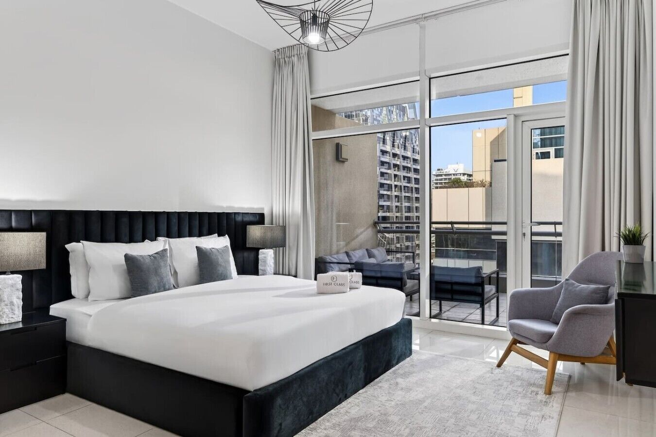 Une chambre d’hôtel moderne dotée d’un grand lit, d’un balcon avec coin salon et d’une vue sur la ville.