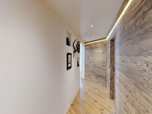 A hallway with wooden flooring, white walls, and a wooden accent wall. - Apartment Di Roz by Interhome (St. Moritz)