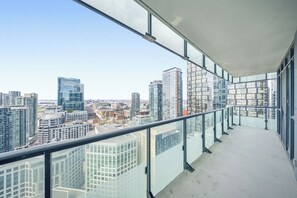 Un balcón con vista a la ciudad, con edificios modernos y cielo despejado.