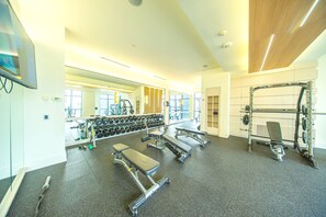 A gym with exercise equipment, a large mirror, and a television. - The Diamond Collection 2 & 3 BDR Suites (Toronto)