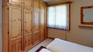 Une chambre avec des armoires en bois, un lit, une fenêtre avec des rideaux et un radiateur.