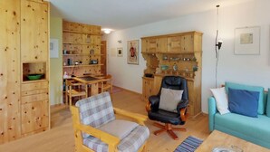 Un salon chaleureux avec des meubles en bois, un coin repas et une cuisine dotée de placards en bois.