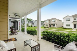 A covered porch with a table and chairs, a ceiling fan, and a view of neighboring houses. - Charming, immaculate coastal home with furnished porches, AC, & washer/dryer (Port Wentworth)