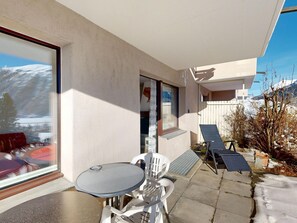 A patio with a table and chairs, a glass door, and a view of a snowy mountain. - Apartment Piz Argient by Interhome (Samedan)