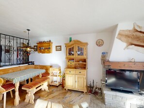 Eine gemütliche Küche mit Holzmöbeln, einem Esstisch, Bänken, einem Schrank und einem Kamin.