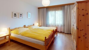 Un letto matrimoniale con cornice in legno, un comodino con lampada e un'ampia finestra con tende.