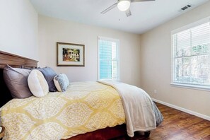 A bedroom with a bed, a ceiling fan, a window with blinds, and a framed picture on the wall. - Renovated bungalow with central AC, W/D, & modern kitchen, Free Wifi (Savannah)