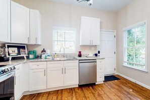 A kitchen with white cabinets, a dishwasher, a stove, and a window with blinds. - Renovated bungalow with central AC, W/D, & modern kitchen, Free Wifi (Savannah)