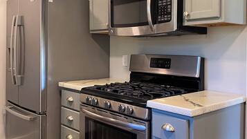 A kitchen with a stainless steel refrigerator, microwave, stove, oven, and a set of drawers.