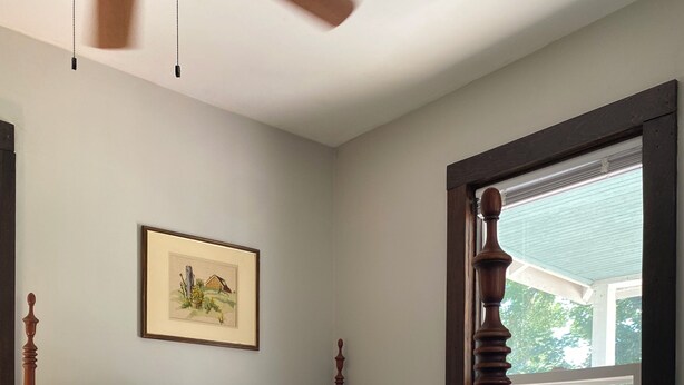 Un dormitorio con una cama con dosel, un cuadro enmarcado en la pared y una ventana con vistas al exterior.
