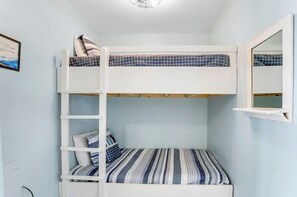 A bunk bed with a ladder, a small bedside table, and a wall-mounted shelf. - Pleasant beach home with central AC, deck & work space - walk to beach & dining (Tybee Island)
