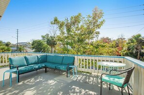 An outdoor patio with a sofa, chairs, and a table. - Pleasant beach home with central AC, deck & work space - walk to beach & dining (Tybee Island)