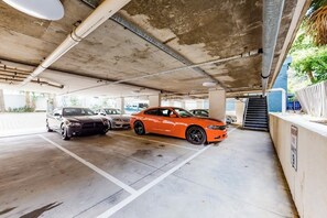 Eine Parkgarage mit Betonpfeilern, einer Rampe und mehreren parkenden Autos.