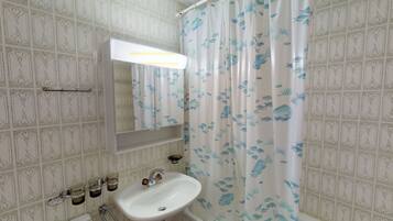 A bathroom with a white sink, a mirror, and a shower curtain with fish patterns.