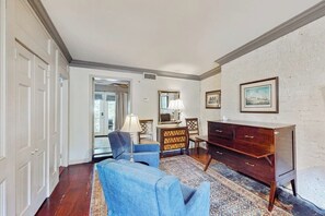 Une pièce avec un fauteuil bleu, une commode en bois et un tapis à motifs.