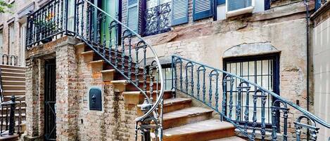 A brick building with a spiral staircase leading to a second-floor landing.