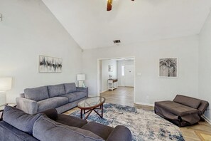 A spacious living room with a grey sofa set, a coffee table, and a patterned rug. - Well-appointed home with spacious backyard, firepit, streaming, & central AC (Savannah)
