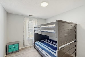 A room with a bunk bed, a small green drawer unit, and a window with curtains. - Well-appointed home with spacious backyard, firepit, streaming, & central AC (Savannah)