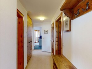 Ein Korridor mit Holztüren, einer Sitzbank und einem gerahmten Bild an der Wand.