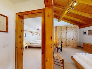 Ein Zimmer mit Holzboden, einem Bett, einem Schreibtisch, einem Sessel und einem Kleiderschrank.